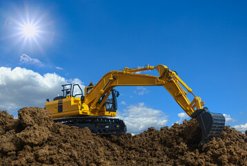 Canvas Print - Yellow excavators are digging the soil in the construction site with the sky and sunbeam background