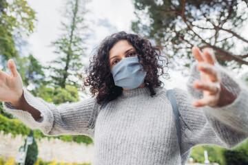 Young woman in a blue mask walking in a park