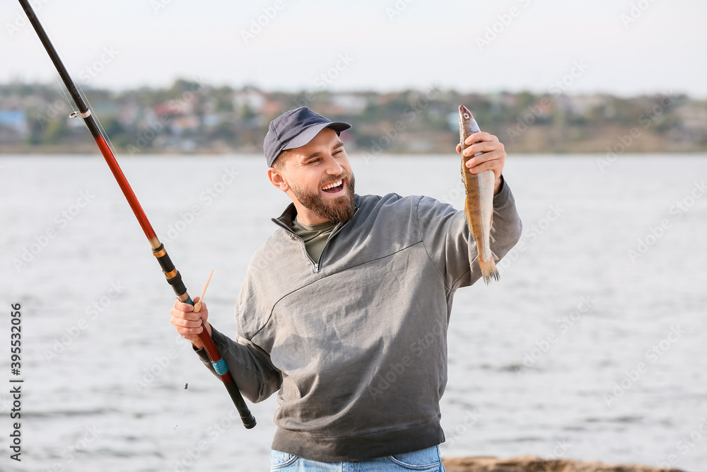 Happy young man fishing on river