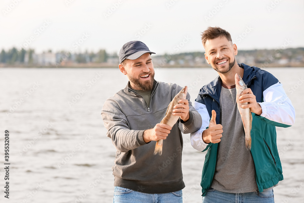 Happy young men fishing on river