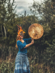 Wall Mural - beautiful shamanic girl playing on shaman frame drum in the nature.