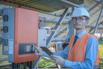 Engineer, a man in uniform checks the control system of the solar station on the background of solar panels