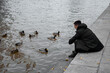 © Denis - A man feeds birds on the street.