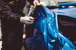 © hedgehog94 - Car wrapping specialist putting vinyl foil or film on car. Selective focus.