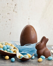 Easter Chocolate Egg In A Blueberry Candy Nest, And A Chocolate Bunny, And A Halved Chocolate Egg Filled With Mini Chocolate Eggs
