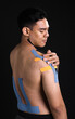 © Ann Rodchua - Portrait of asian muscular man getting pain and putting kinesiology tape on his body