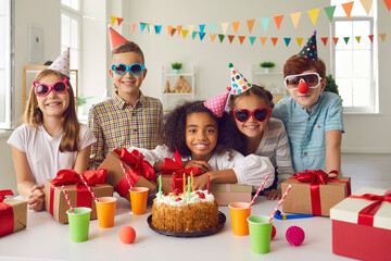 Portrait of an afro american birthday girl with her friends who are at the table with presents.