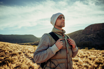 Wall Mural - Smiling Caucasian male hiker walking through mountain terrrain 