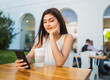 © Mego-studio - Young woman using her phone at coffee shop.