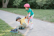 © anoushkatoronto - Girl helping boy to stand up on roller blades after falling. Caucasian friends boy and girl riding on roller skates in park on summer day. Seasonal outdoors children activity sport. Kids summer sport.