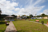 Fototapeta Tęcza - village park with green areas, kiosk and church on a sunny day
