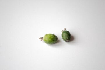 two isolated feijoas on a white background