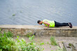 © Georgii - Sporty male in sportswear working out, doing push ups or press ups outdoors on summer day near water