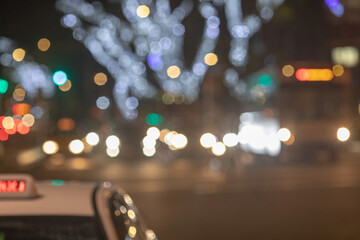 The big taxi sign on the blurred background of night city. Taxi driving at high speed through the heavy traffic at night.