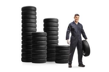 Wall Mural - Piles of tires and an auto mechanic worker holding a car tire