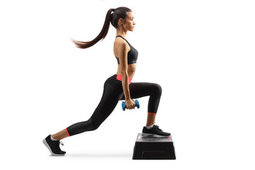 Wall Mural - Young woman exercising step aerobic with small weights