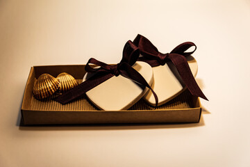 Two white hearts and shells in a brown gift box.