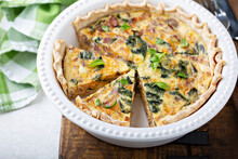 Spinach And Bacon Quiche Cut Up In A Baking Dish