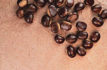 Canvas Print - Top view of fresh chestnuts on a brown surface with copy space