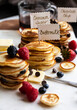 © Foodlovers - Stacks of mini pancakes with signs, with fruit and chocolate chips, syrup and butter, on a marble board