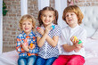 © Maxim - Easter children portrait, funny emotions, surprise. Children, a girl and two boys hold Easter eggs in their hands. Funny photo. Adorable kid in colored clothes enjoying holiday
