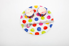 High Angle View Of Cupcakes In Multicolored Plate Against White Background