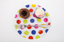 Top View Of Cupcakes In Multicolored Plate Over White Background