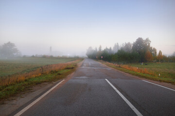 Wall Mural - Panoramic view of the empty highway through the fields and forest in a fog at sunrise. Europe. Transportation, logistics, travel, road trip, freedom, driving. Rural scene