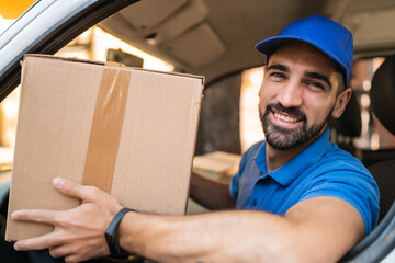 Delivery man holding cardboard boxes in van.