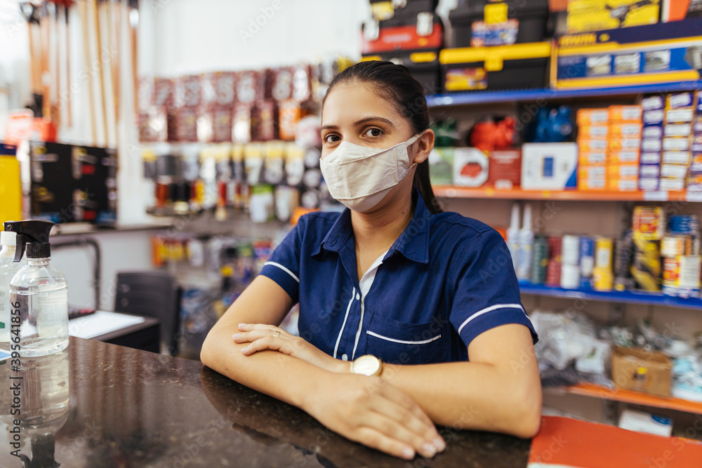 Young woman wearing face mask working in hardware store - obrazy, fototapety, plakaty 