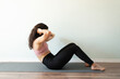 © AntonioDiaz - Athletic woman in her 20s in the middle of doing abdominal crunches