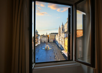 Early morning view from an open window overlooking Piazza Navona as sunlight lights the dome on the St. Agnes Cathedral