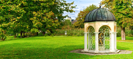 A small chapel in the park by lake promenade near the city of Mondsee , Austria