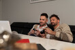 © CameraCraft - Young gay couple playing video games using joystic controller. Lifestyle of same sex partners. High quality photo