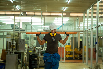 Factory worker in the hard hat and working about mechanical piece at old factory equipment.