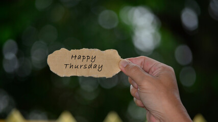 Wall Mural - Happy Thursday Text On Hands Holding Torn Paper With Blurred Dark Background