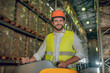 © zinkevych - Warehouse worker in orange helmet standing near shelves with containers and smiling