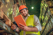 © zinkevych - Warehouse worker in yellow vest looking at the tablet and looking serious