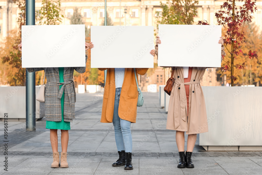 Beautiful young women with blank posters outdoors