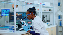 African Scientist Checking Sample Of Virus Using Microscope In Modern Lab. Multiethnic Team Examining Vaccine Evolution Using High Tech For Scientific Research Of Treatment Development Against Covid19