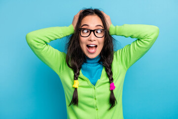 Poster - Photo of positive funky young woman crossed eyes hold hands head crazy mood wear glasses isolated on blue color background