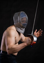 Matured Man With Naked Muscular Torso In Fencing Helmet And Epee