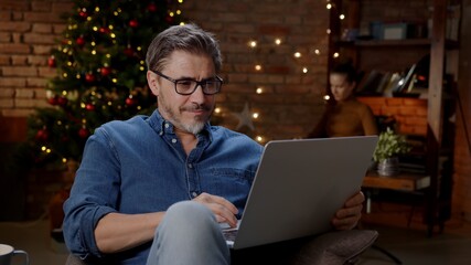 Couple at home in Winter. Man working from home with Laptop computer.