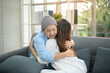 © tonefotografia - Cancer patient woman wearing head scarf hugging her supportive daughter indoors, health and insurance concept.