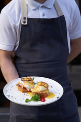 Waiter holding breakfast tray with Eggs Benedict