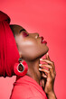 © LIGHTFIELD STUDIOS - profile of african american woman in stylish outfit and turban with closed eyes isolated on red