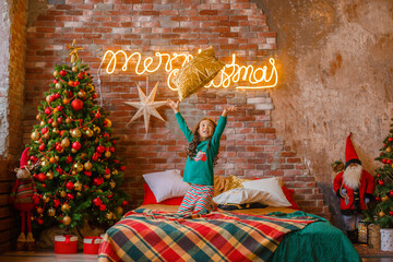 Wall Mural - little girl Asian girl in her pajamas in the bedroom messing around on the cushions, Christmas, new year