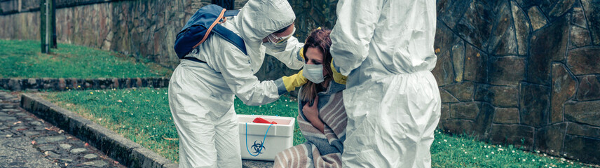 Sticker - Doctors putting protective mask on woman infected by a virus outdoors