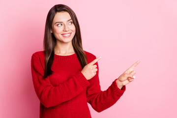 Wall Mural - Photo portrait of beautiful smiling brunette wearing warm sweater pointing on copyspace space with both hands looking at side isolated on pink color background