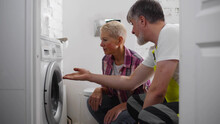 Senior Repairman Fixing Washing Machine For Woman Client